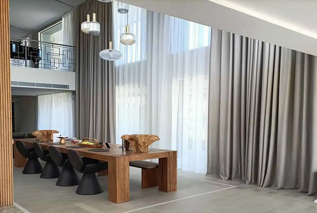 Cortinas dobles con tal transparente de lino y tejido blackout textil en un salón de estilo nórdico en colores neutros instaladas por cortinas Madegae en un riel de guia doble